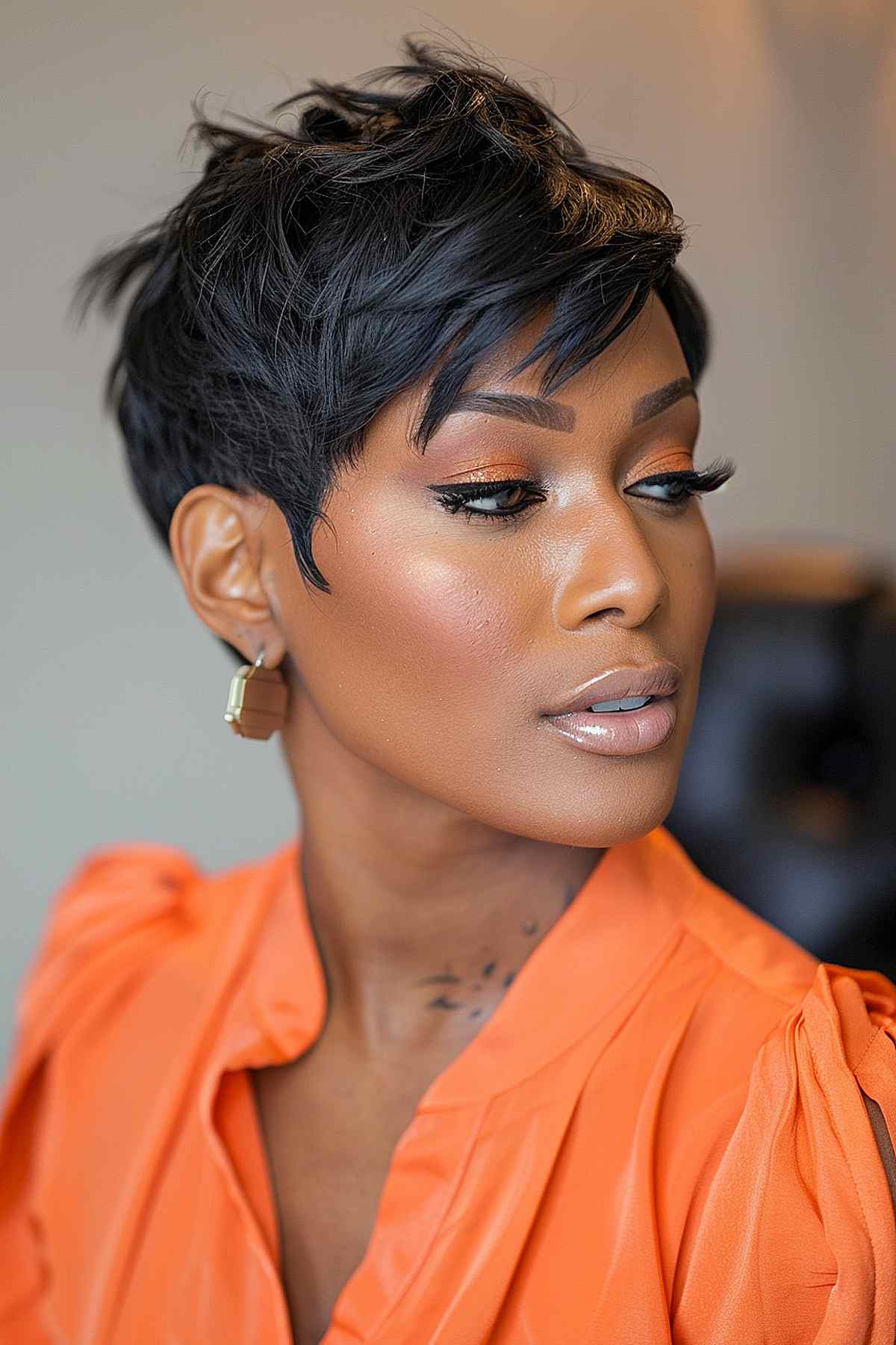 Black woman with a short feathered pixie cut, emphasizing voluminous texture and feathered bangs, suitable for square or round face shapes.